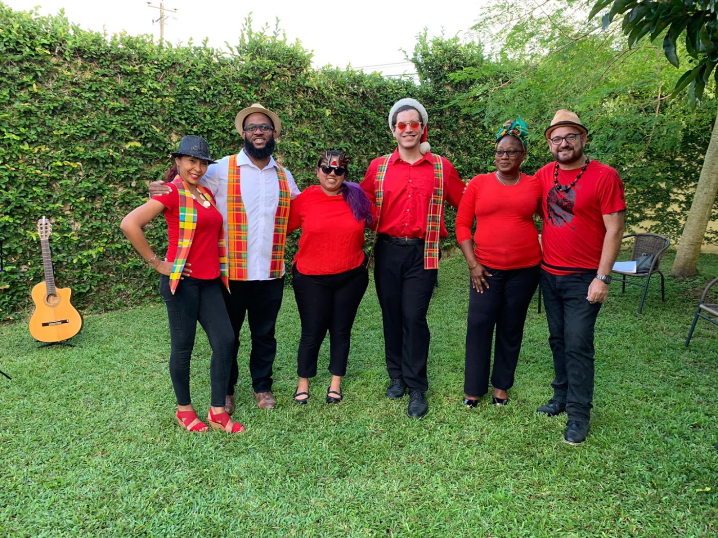 Choir members dressed in red with Madras sashes, smiling together on a lawn